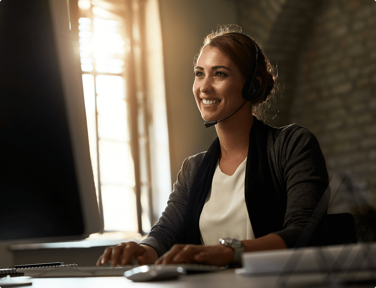 A woman wearing a headset is sitting at a computer and helping a UsenetServer customer.