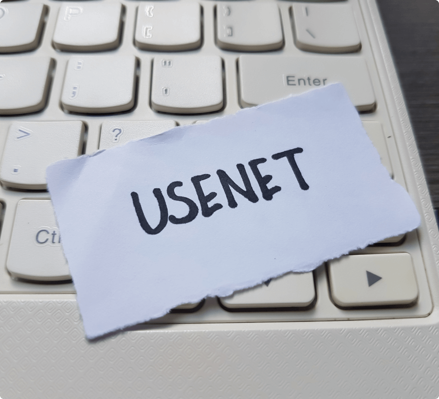 The word ‘Usenet’ written on a piece of paper on a computer keyboard, symbolizing the ‘news’ Usenet newsgroup for discussing the latest news.