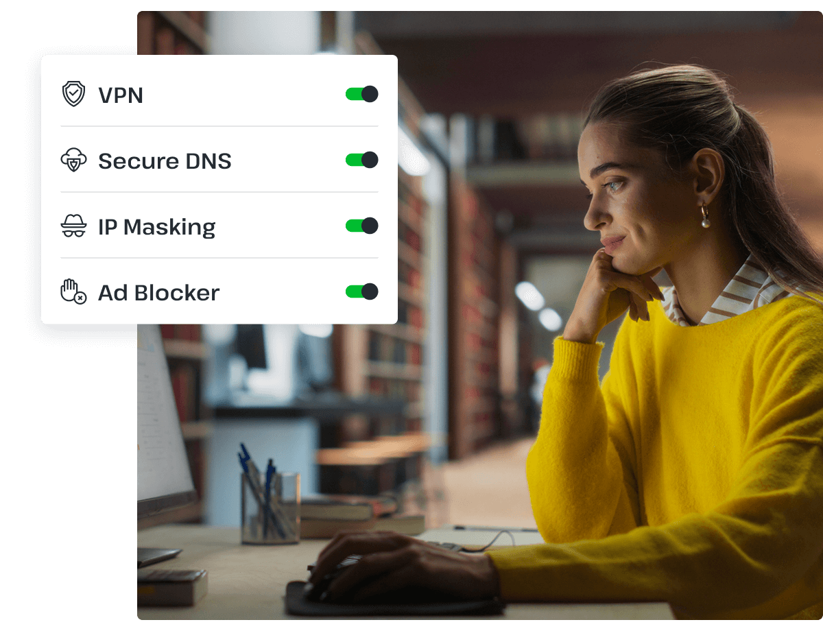 A woman in a yellow sweater is reading something on her desktop with her hand resting on the keyboard.