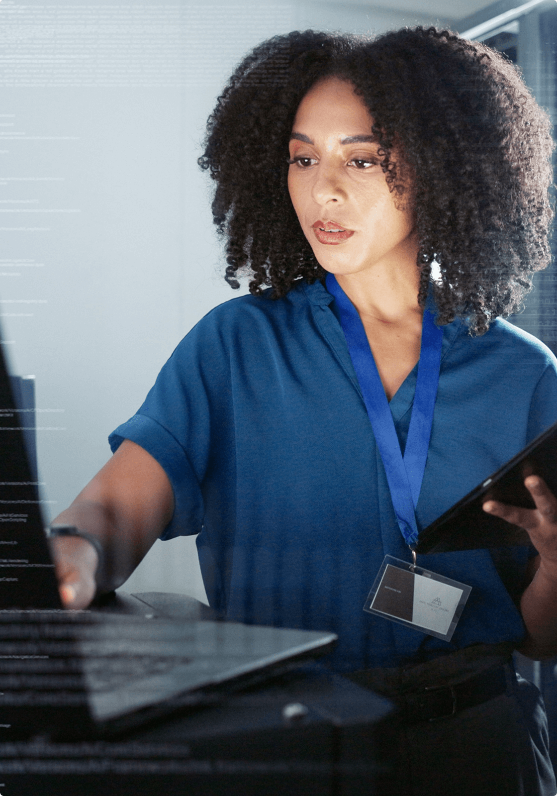 A woman with a tablet works on a laptop to repair a computer issue, representing the consistent maintenance of servers done by UsenetServer.